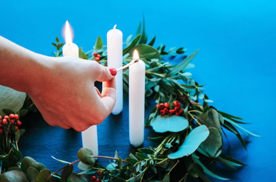 Cropped hand of woman igniting candle