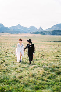 Rear view of woman standing on field against clear sky