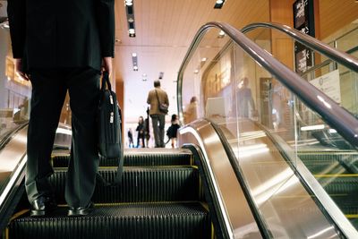 Low section of people walking on escalator