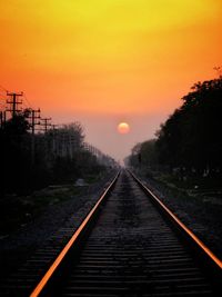 Railroad tracks against sky during sunset