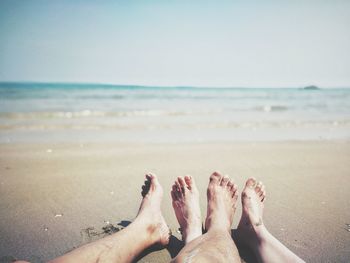 Low section of couple relaxing on beach