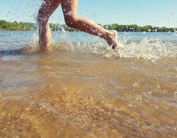 Low section of man splashing water in sea