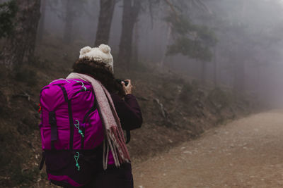 Rear view of female hiker on footpath amidst trees in forest