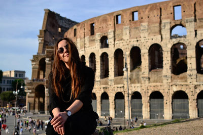 Mid adult woman sitting with coliseum in background