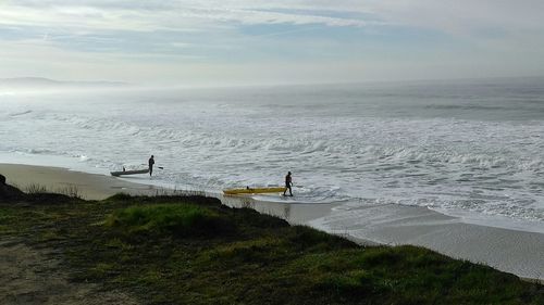 High angle view of people with kayaks walking at beach