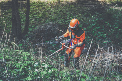 Man holding a brush cutter cut grass. lumberjack at work. gardener working outdoor in the forest
