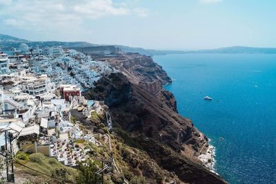 Buildings on mountains by sea against sky