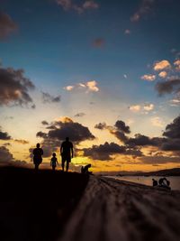 Silhouette people walking on road against sky during sunset