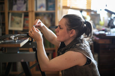 Craftsman woman works with decoration, makes the base of copper metal under the enamel, the concept 