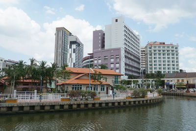 Buildings by river against sky in city