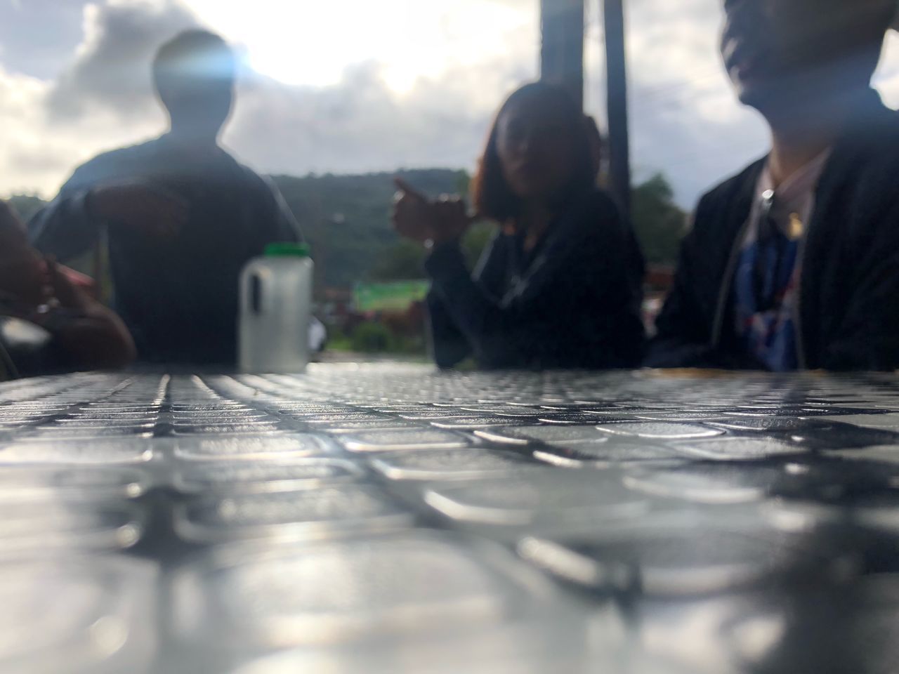 REAR VIEW OF PEOPLE SITTING ON TABLE OUTDOORS