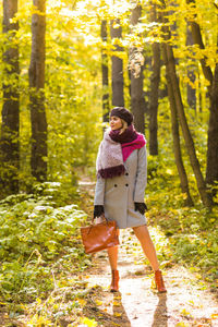 Full length of young woman standing in forest