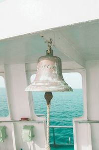 Close-up of electric lamp hanging by sea against sky
