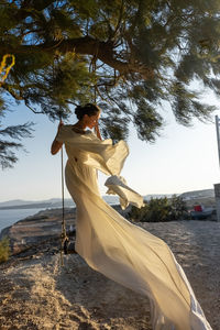 Rear view of woman with arms outstretched standing on hammock