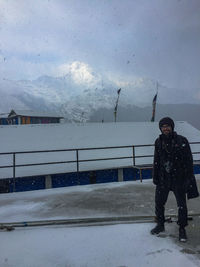 Man standing on snowcapped mountain against sky
