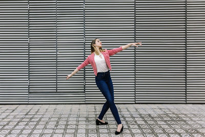 Full length of woman standing on umbrella in city