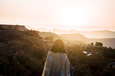 Rear view of woman standing on mountain against sky