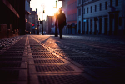 Surface level view of person walking on street in city during sunset