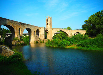 Arch bridge over river against sky