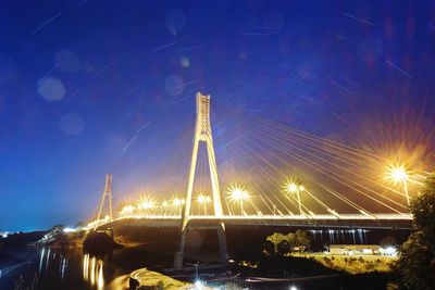 Illuminated bridge over river against sky at night