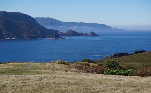 Scenic view of sea and mountains against clear blue sky