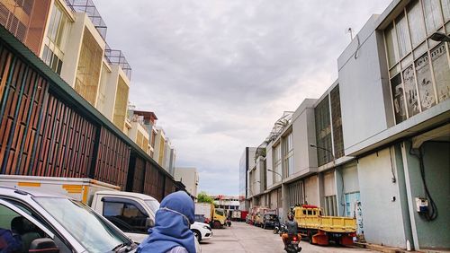 Man on street amidst buildings in city against sky