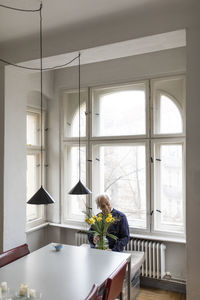 Senior man with bunch of flowers sitting at table at home