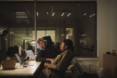 Businesswoman talking with male colleague sitting at work place