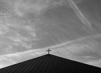 Low angle view of cross on roof of building against sky