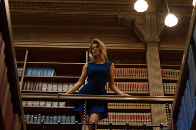 Low angle view of thoughtful woman leaning on railing at library