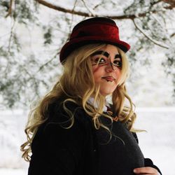 Portrait of young woman wearing hat against trees during winter