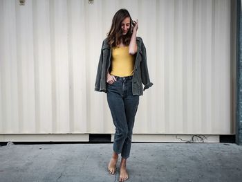 Portrait of young woman standing against wall