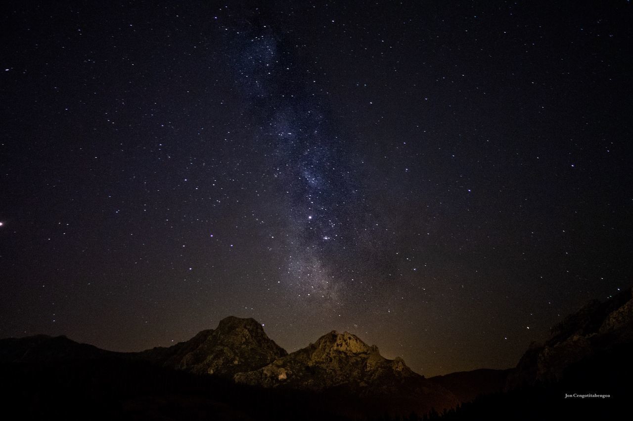 LOW ANGLE VIEW OF MOUNTAIN AGAINST STAR FIELD