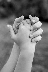 Close-up of bride and groom with clasped hands outdoors