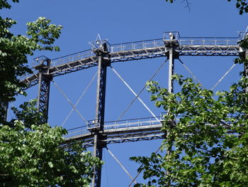 Low angle view of electricity pylon against blue sky