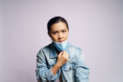 Portrait of young woman wearing mask against white background