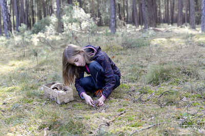 Cute girl collecting edible mushroom in forest