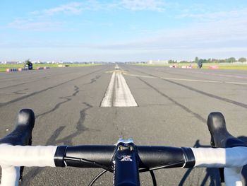 Close-up of hand on bicycle against sky