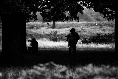 Rear view of silhouette people standing on grassy field