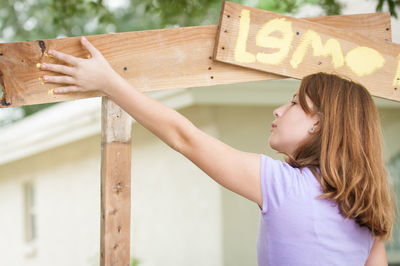 Rear view of girl holding text on wood