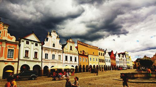 People in town square against cloudy sky