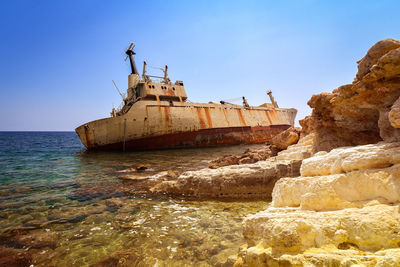 Abandoned ship in sea against clear sky