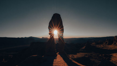 Sun seen through rock object against sky