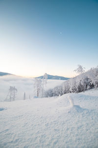 Morning idyll on the top of a snow-covered mountain with the rays of the sun irradiating the clouds