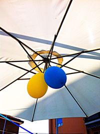 Low angle view of colorful lights hanging against blue sky