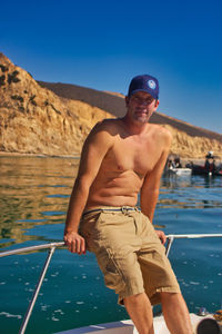 Portrait of shirtless man in sea against sky