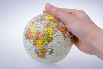 Close-up of woman hand holding globe against white background