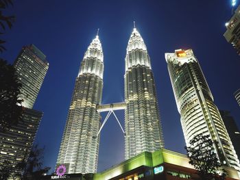 Low angle view of skyscrapers lit up against sky