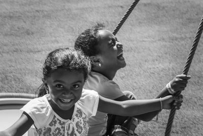 Portrait of smiling girls on swing at playground