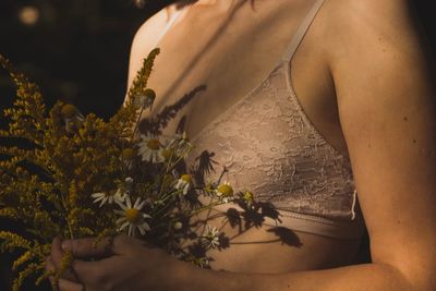 Midsection of woman by flowering plants